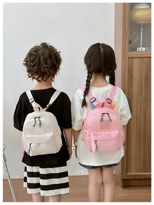 Vue arrière de bambins portant des mini sacs à dos en nylon crème et rose pastel