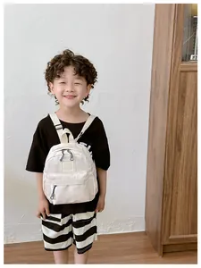 Détail d'un sac à dos enfant en nylon crème avec poches zippées et patch logo