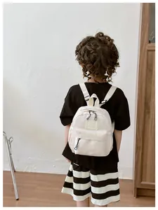 Détail du sac à dos beige pour enfant avec poche zippée et logo GIDL CAES brodé