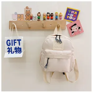 Vue détaillée du sac à dos enfant crème avec logo GIDL CAES et tirettes grises