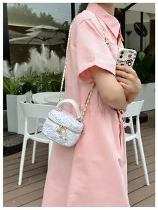 Détail du mini sac bandoulière blanc à paillettes avec chaîne et charm boule en métal