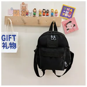 Détail d'un mini sac à dos noir pour enfant avec tirettes en caoutchouc et logo GIDL CAES