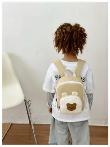 Rear view of a cute bear embroidery canvas kids backpack worn by a toddler model