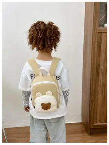 Back view of a child wearing a cute khaki and cream mini backpack with bear ears