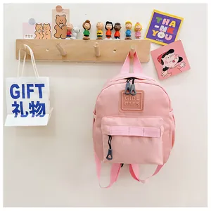 Mini sac à dos rose pour enfant accroché à un support en bois au décor mignon