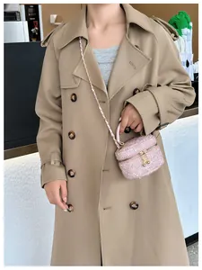 Détail d'un mini sac rose en tweed à paillettes avec bandoulière dorée sur un trench-coat