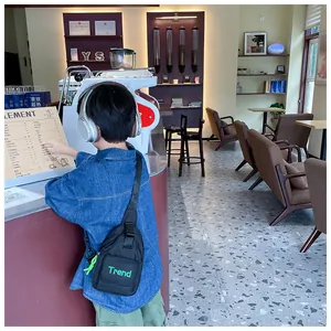 Kid's black nylon chest bag with green 'Trend' lettering and adjustable shoulder strap