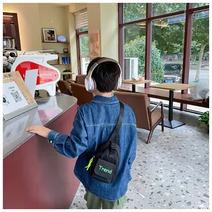 Detail of black nylon kids chest bag with green Trend text and adjustable buckle strap