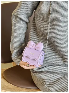 Detail of mini lavender bow bag with wave-edge flap and silver metal chain strap