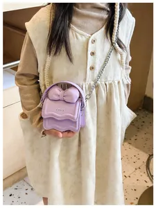 Detail view of purple mini crossbody bag with a 3D bow and silver chain on a child model