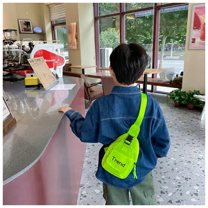 Detail of neon green kids chest bag featuring trend lettering and adjustable strap