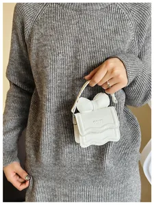 Detail of white mini handbag with large bow, wavy edge and FAVE embossed lettering