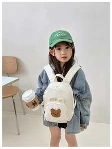 Close-up of cute 3D bear ears and brown bear embroidery on a cream canvas kids backpack