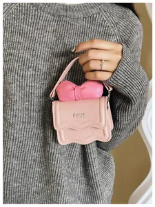 Detail of pink mini bag with bow, wave edge flap, and silver FAVE metal logo