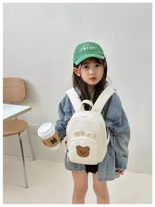 Close-up of cute bear embroidery on a minimalist beige toddler backpack for nursery