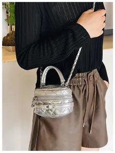 Detailopname van een zilveren gewatteerde mini-crossbodytas met metallic finish en ketting