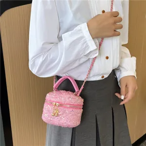 Sac bandoulière rose à paillettes avec chaîne porté par un mannequin élégant