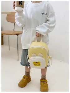 Detail showing a yellow canvas toddler backpack with a cute cartoon bear and white straps