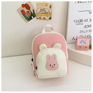 Close-up of pink and cream bunny backpack with 3D ears on a cozy white desk