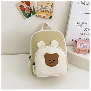 Close-up of small canvas backpack featuring cute bear embroidery and color blocking