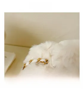 Macro shot of cream white faux fur texture and golden metal chain strap on fashion bag
