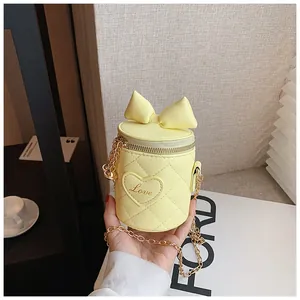 Detail of light yellow bucket bag with quilted patterns, bow, and Love heart patch