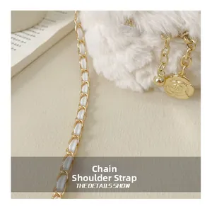 Detailed close-up of white plush bag with golden chain strap and camellia charm