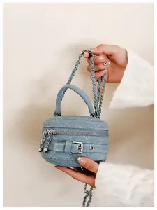 Close-up of light blue denim quilted bag with silver double zippers and metal chain strap