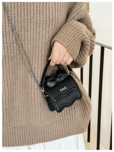 Detailed texture of black mini crossbody bag with leather bow and wave quilting pattern