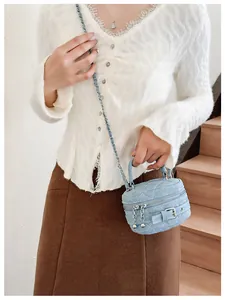 Detail of light blue denim quilted mini bag with silver chain and crossbody strap