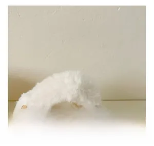 Close-up of white plush handbag showing soft faux fur texture and golden chain strap
