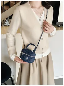 Detail of denim blue quilted mini crossbody bag with gold chain and circular zipper closure