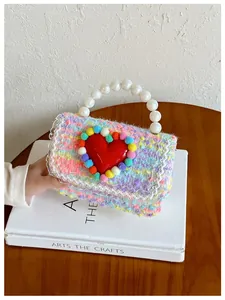 Dettaglio macro della mini borsa lavorata a maglia con manico di perle e cuore rosso