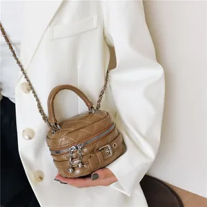 Bruine mini gewatteerde crossbodytas met metalen ketting gedragen door een model