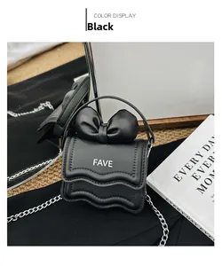 Detail of black mini handbag featuring a large bow and silver metal chain strap