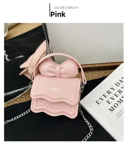 Detail view of pink mini crossbody bag with large bow handle and silver chain strap