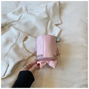 Detailed view of pink quilted bucket bag with bow ornament and gold chain strap