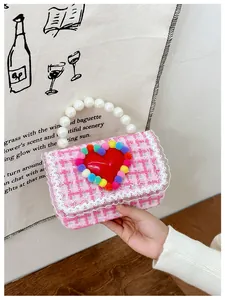 Dettaglio borsa bimba in tweed rosa con cuore rosso, pompon colorati e manico perla