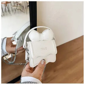 Detailed mirror view of a creamy white mini bow bag with FAVE logo and metal chain strap
