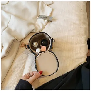 Close-up of small black bucket bag showing capacity for lipstick and perfume inside