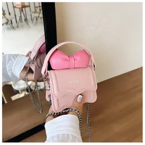 Detail of pink mini bag with bow, wave edge flap and embossed FAVE lettering