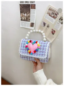 Dettaglio borsa a tracolla in tweed con manico di perle, cuore rosa e pompon