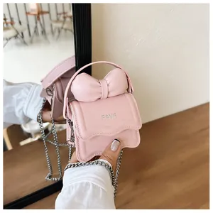 Close-up of light pink mini bag featuring a large bow and gold chain strap detail