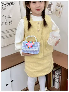 Dettaglio borsa a tracolla in tweed per bambini con manico di perle e decoro a cuore