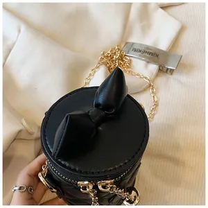 Detail of black quilted bucket bag with leather bow and gold chain strap close-up