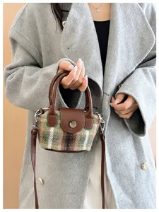 Dettaglio di una mini borsa vintage a quadri verdi con finiture in pelle marrone