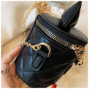 Detail view of quilted black bucket bag with golden chain strap and bell charm