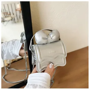 Detail of silver metallic mini bag featuring a large bow and FAVE logo with chain strap