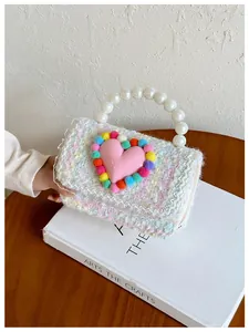 Dettaglio mini borsa in tweed per bambini con manico di perle e cuore di peluche