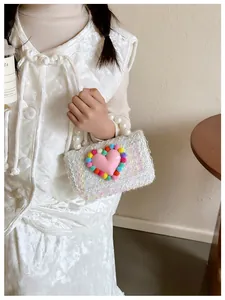Borsa a tracolla in tweed per bambina con manico di perle e cuore di peluche indossata